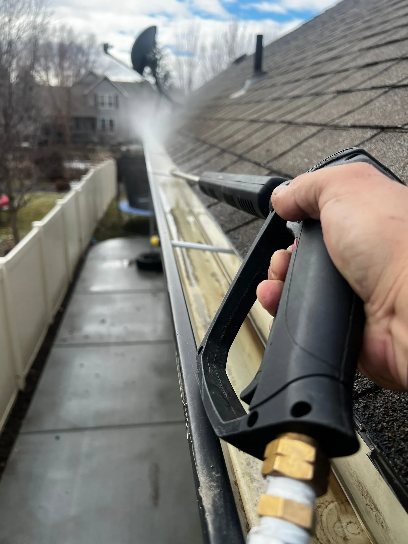 First-person view of a gutter being flushed clean along a shingle roof